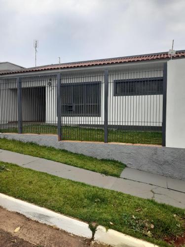 a building with a fence next to a sidewalk at Casa com piscina in Ourinhos