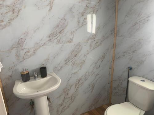 a white bathroom with a toilet and a sink at Casa de Mar in Quellón