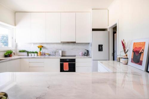 a white kitchen with white cabinets and a black appliance at Big apt 4beds with terrace, 15 mins to Lisbon in Almada