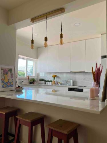 a large kitchen with white cabinets and stools at Big apt 4beds with terrace, 15 mins to Lisbon in Almada
