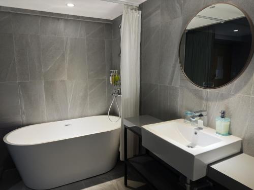 a bathroom with a tub and a sink and a mirror at Cho Hotel 3 in Taipei
