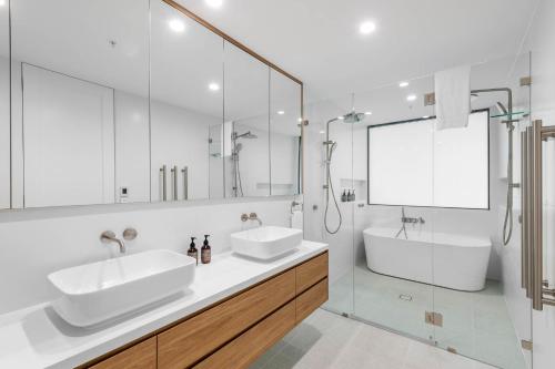 a white bathroom with two sinks and a shower at Kove Apartments Kiama in Kiama