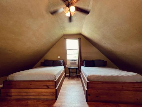 a attic bedroom with two beds and a window at Treehouse 1 Mockingbird Lodge in New Braunfels
