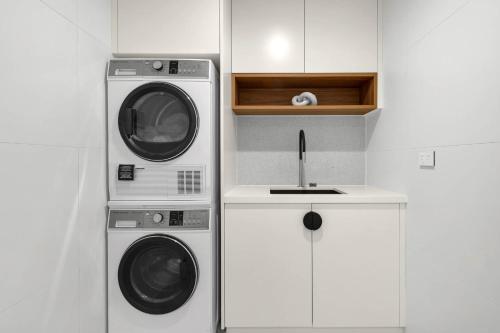 a kitchen with two washing machines and a microwave at Kove Apartments Kiama in Kiama