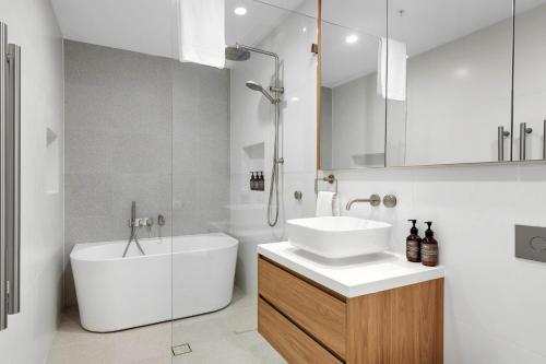 a bathroom with a white sink and a tub and a mirror at Kove Apartments Kiama in Kiama