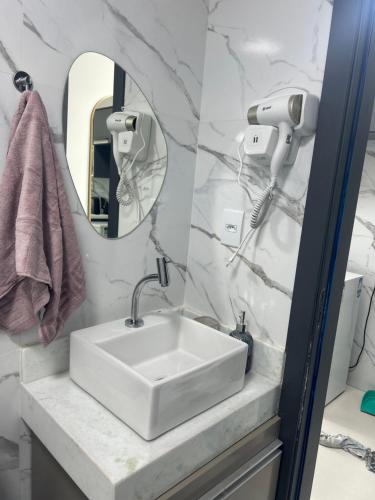Un baño con un lavabo blanco y un espejo. en Flat makani carneiros tamandare, en Tamandaré