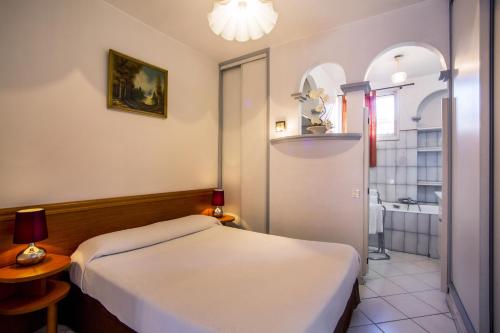 a small bedroom with a bed and a bathroom at Hotel le Dauphin in Ajaccio
