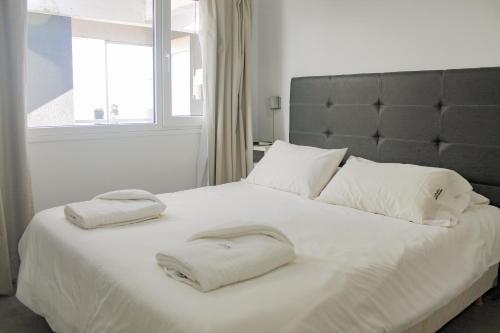 a bedroom with a white bed with two towels on it at Complejo Espacio Marina in Villa Gesell
