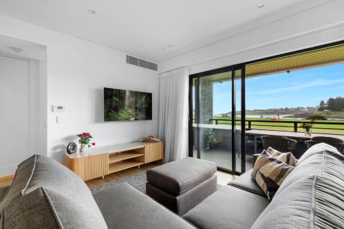 a living room with a couch and a large window at Kove Apartments Kiama in Kiama