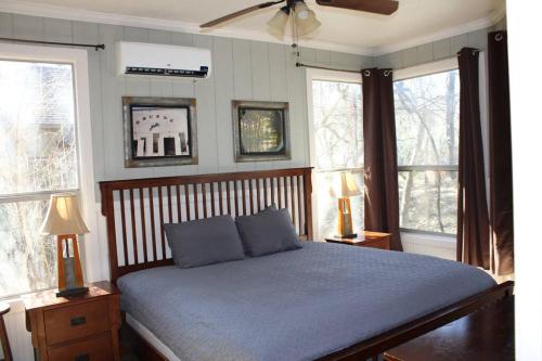 een slaapkamer met een bed met blauwe lakens en ramen bij Treehouse 5 - Robins Roost in New Braunfels