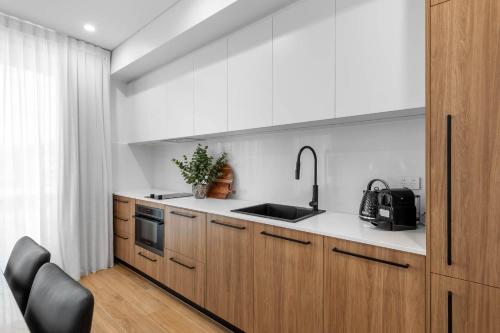 a kitchen with wooden cabinets and a sink at Kove Apartments Kiama in Kiama