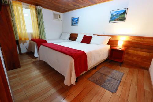 a bedroom with a large bed with a red blanket at Hospedaria Brigite - Apartamento de Férias in Treze Tílias