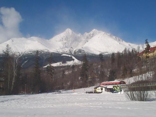 a snow covered mountain with a house in the foreground at Apartman Tri Duby Tatranská Lomnica in Tatranská Lomnica