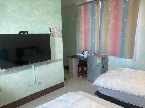 a bedroom with a bed and a flat screen tv at 福田民宿 台東民宿476號 in Guanshan