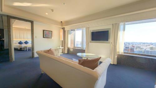 a living room with a couch and a large window at Premier Hotel Nakajima Park Sapporo in Sapporo