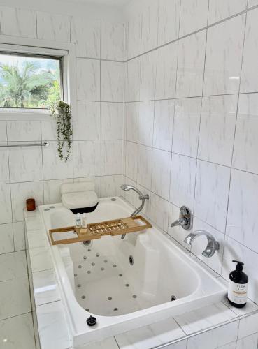 a white bathroom with a tub and a window at Mountain Views, Spa Bath, Pet Friendly, Near Zoo! in Glass House Mountains