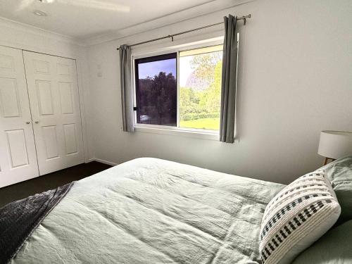 a bedroom with a bed and a window at Mountain Views, Spa Bath, Pet Friendly, Near Zoo! in Glass House Mountains