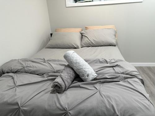 a bed with gray sheets and pillows on it at Luxury-Home Away from Home with Private Entrance in Winnipeg