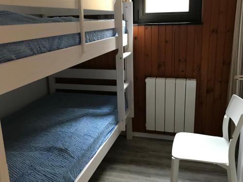 a bunk bed room with two bunk beds and a chair at Appartement central à Super Besse, 2 chambres, proche pistes - FR-1-814-11 in Besse-et-Saint-Anastaise