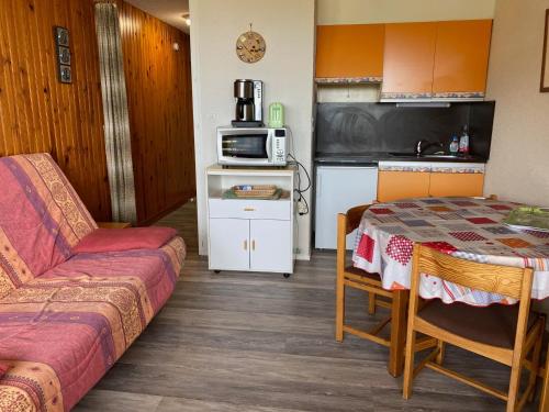 une petite pièce avec une table et une cuisine dans l'établissement Studio au centre station avec balcon et parking gratuit - FR-1-814-12, à Besse-et-Saint-Anastaise