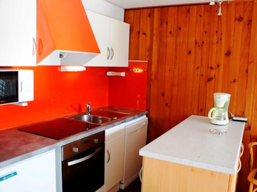 - une cuisine avec un évier et un mur orange dans l'établissement Appartement skis aux pieds, F2+Cabine au 20ème étage - FR-1-814-25, à Besse-et-Saint-Anastaise