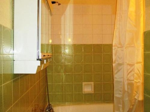 La salle de bains est pourvue de carrelage vert, d'une douche et d'un lavabo. dans l'établissement Appartement coeur de station avec parking privé à Super Besse - FR-1-814-47, à Besse-et-Saint-Anastaise