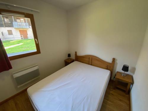 une chambre avec un lit blanc et une fenêtre dans l'établissement Appartement avec terrasse et piscine proche nature à Super-Besse - FR-1-814-52, à Besse-et-Saint-Anastaise