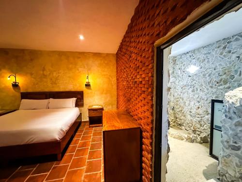 a bedroom with a bed and a brick wall at Le Suisse Spa in Santa Lucía Milpas Altas