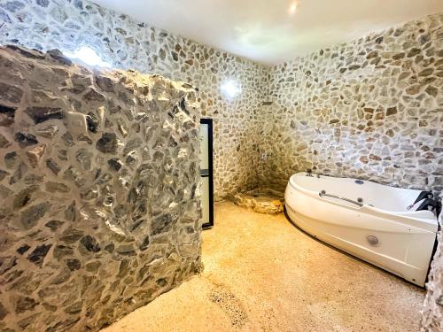 a bathroom with a tub and a stone wall at Le Suisse Spa in Santa Lucía Milpas Altas