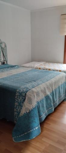a bed with a blue blanket sitting on a wooden floor at Casa Nahuel in Algarrobo