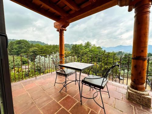 a table and chairs on a patio with a view at Le Suisse Spa in Santa Lucía Milpas Altas