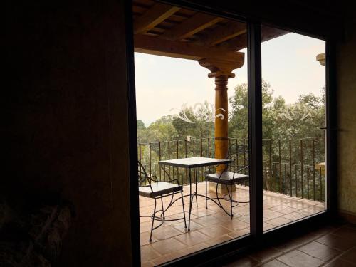 a room with a balcony with a table and chairs at Le Suisse Spa in Santa Lucía Milpas Altas