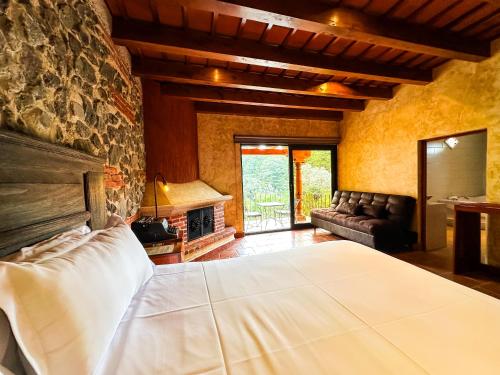 a bedroom with a bed and a stone wall at Le Suisse Spa in Santa Lucía Milpas Altas