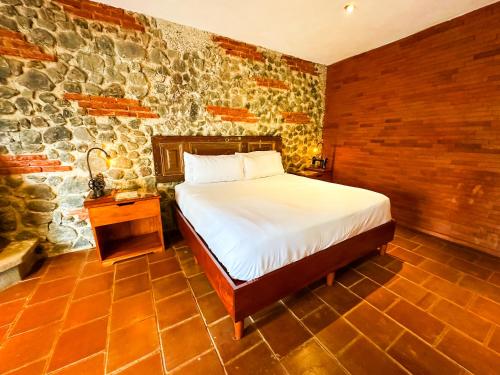 a bedroom with a bed and a stone wall at Le Suisse Spa in Santa Lucía Milpas Altas