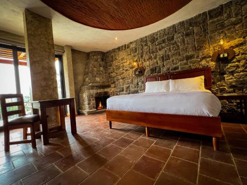 a bedroom with a bed and a stone wall at Le Suisse Spa in Santa Lucía Milpas Altas