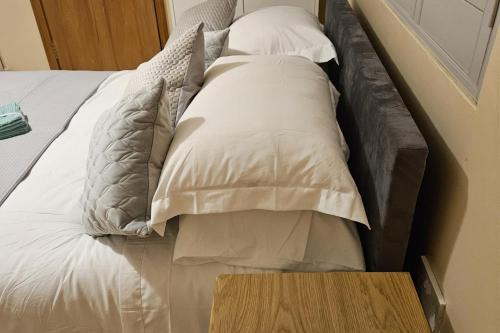 a bed with white pillows on it with a wooden table at Cosy London Apartment with Great Views in London