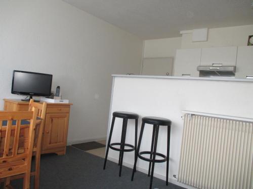 Cette chambre dispose de deux tabourets de bar et d'un comptoir avec une télévision. dans l'établissement Appartement 4 pers près centre et pistes, navette, parking, lave-vaisselle - FR-1-814-74, à Besse-et-Saint-Anastaise
