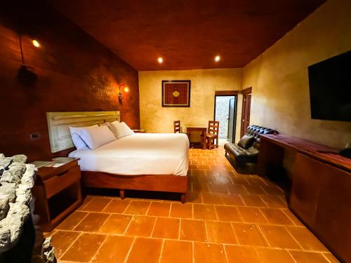 a bedroom with a bed and a flat screen tv at Le Suisse Spa in Santa Lucía Milpas Altas