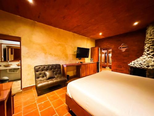 a bedroom with a bed and a desk and a chair at Le Suisse Spa in Santa Lucía Milpas Altas