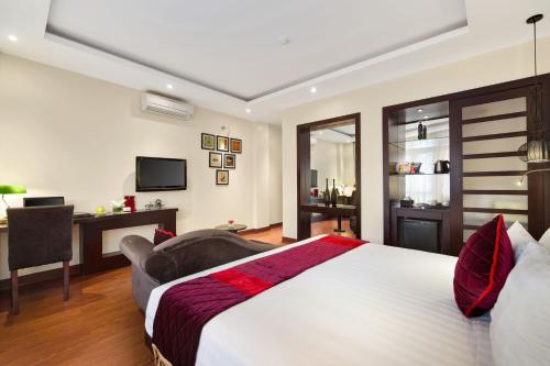a bedroom with a large bed with a desk and a chair at Hanoian Central Hotel & Spa in Hanoi