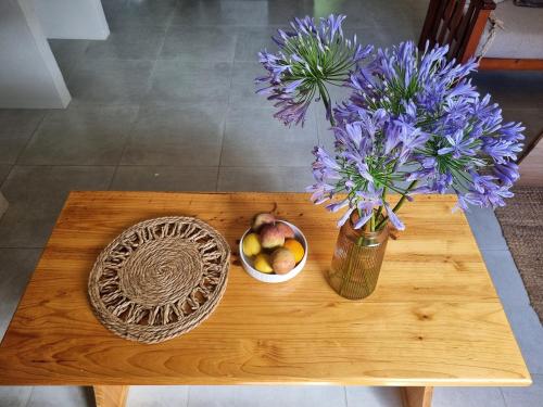 a table with a vase of purple flowers and a basket of fruit at Lambertshoek Farm Stay in Graafwater