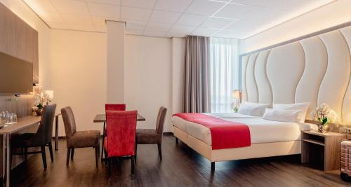 a hotel room with a bed and a table and chairs at PLAZA Premium Almere in Almere