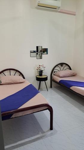 a room with two beds and a table with flowers at Aja Retreat Bungalow OnlyMuslim in Jitra