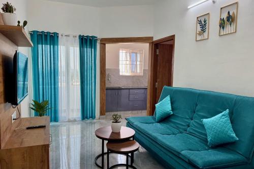 a living room with a blue couch and a table at Truelife Whitefield - Premium 1 BHK Apartments - Prime location - Easy access to Main Rd - Metro - ITPL - Fast WiFi - Kitchen - Smart TV - Power backup - Park - Garden views in Bengaluru
