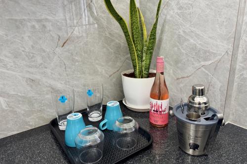 a tray with a bottle of wine and glasses and a potted plant at Truelife Whitefield - Premium 1 BHK Apartments - Prime location - Easy access to Main Rd - Metro - ITPL - Fast WiFi - Kitchen - Smart TV - Power backup - Park - Garden views in Bengaluru