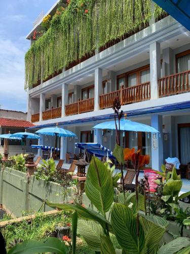 a hotel with chairs and umbrellas in front of it at Komodo Lodge in Labuan Bajo