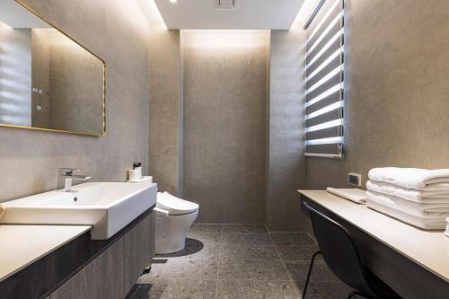 a bathroom with a sink and a toilet and a mirror at Triple Suite Villa BnB in Magong