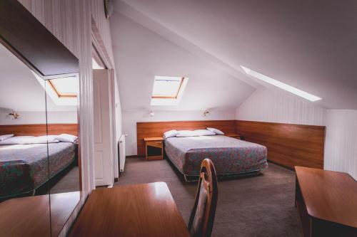 ワルシャワにあるホテル ツインズのベッド2台、テーブルと椅子が備わるホテルルームです。