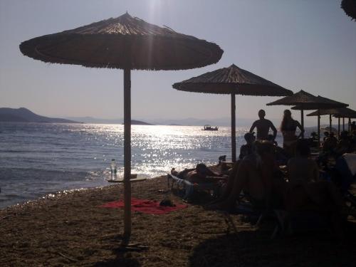 a group of people sitting on a beach under umbrellas at Villa Bellevue in Nea Stira