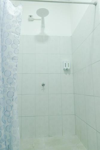 a white bathroom with a shower with a shower curtain at Suite Tierra, Reconnect with your roots in Puerto Baquerizo Moreno